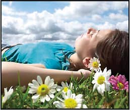 Girl laying in a field surrounded by flowers with her eyes shut