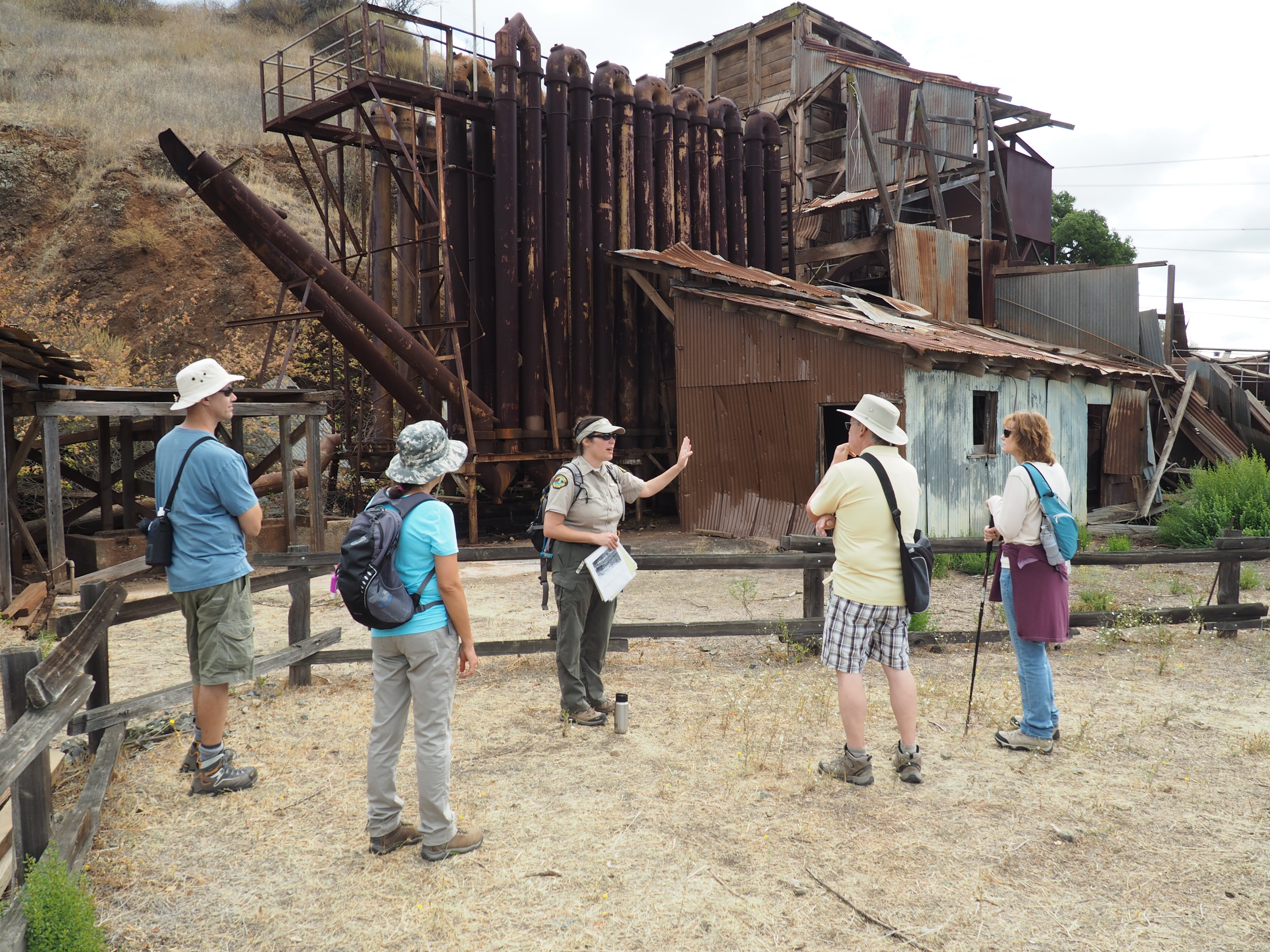 Park intepreter talks with program participants in front of furnace within Almaden Quicksilver County Park