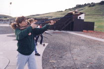 A woman shooting a shotgun on a skeet range