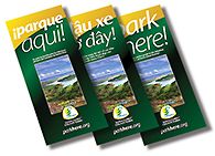 Three "Park Here!" brochures in Spanish, Vietnamese, and English