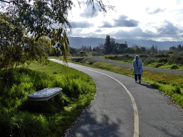 Woman walking along a paved trail at the Los Gatos Creek Park
