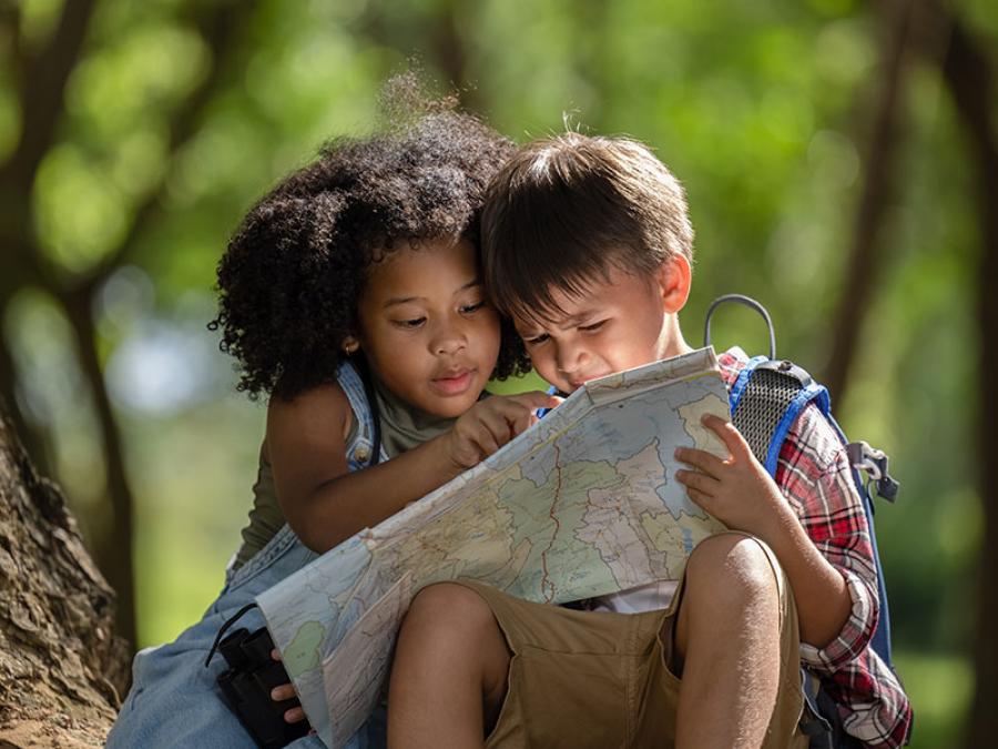 Two children looking at a paper map together