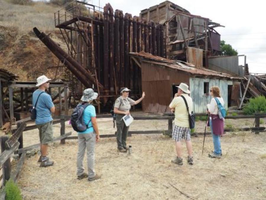 A Park Interpreter talking to visitors outside a large furnace within Almaden Quicksilver County Park