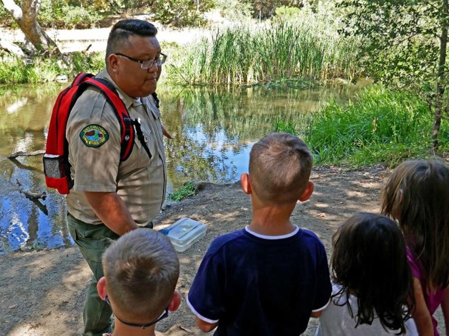 Park interpreter talking to children by creek