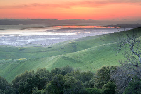 Sunset over the green hills of Ed Levin County Park, with Milpitas in the distance below.