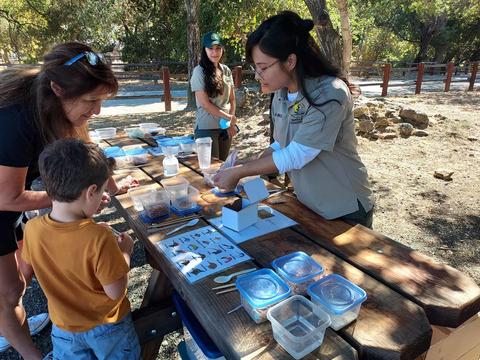 Park Staff showing junior archeology activity instructions to parent and child
