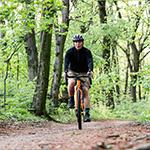 Man biking on a dirt path surrounded by trees