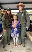 Young girl standing between two Santa Clara County Parks staff. All are smiling and looking at the camera.