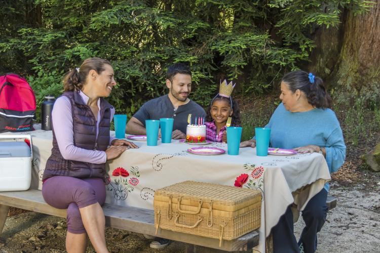 A family sitting at a campsite picnic table smiling