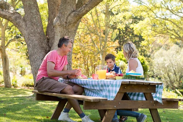 Happy family eating together at a park picnic table
