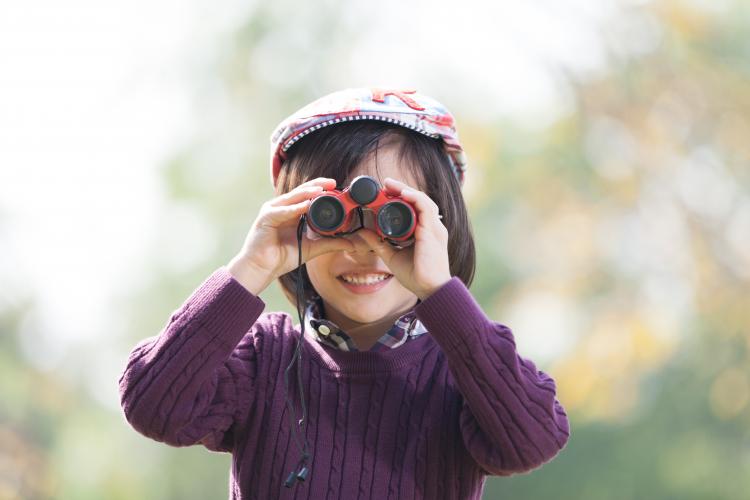 A child looking at nature through binoculars